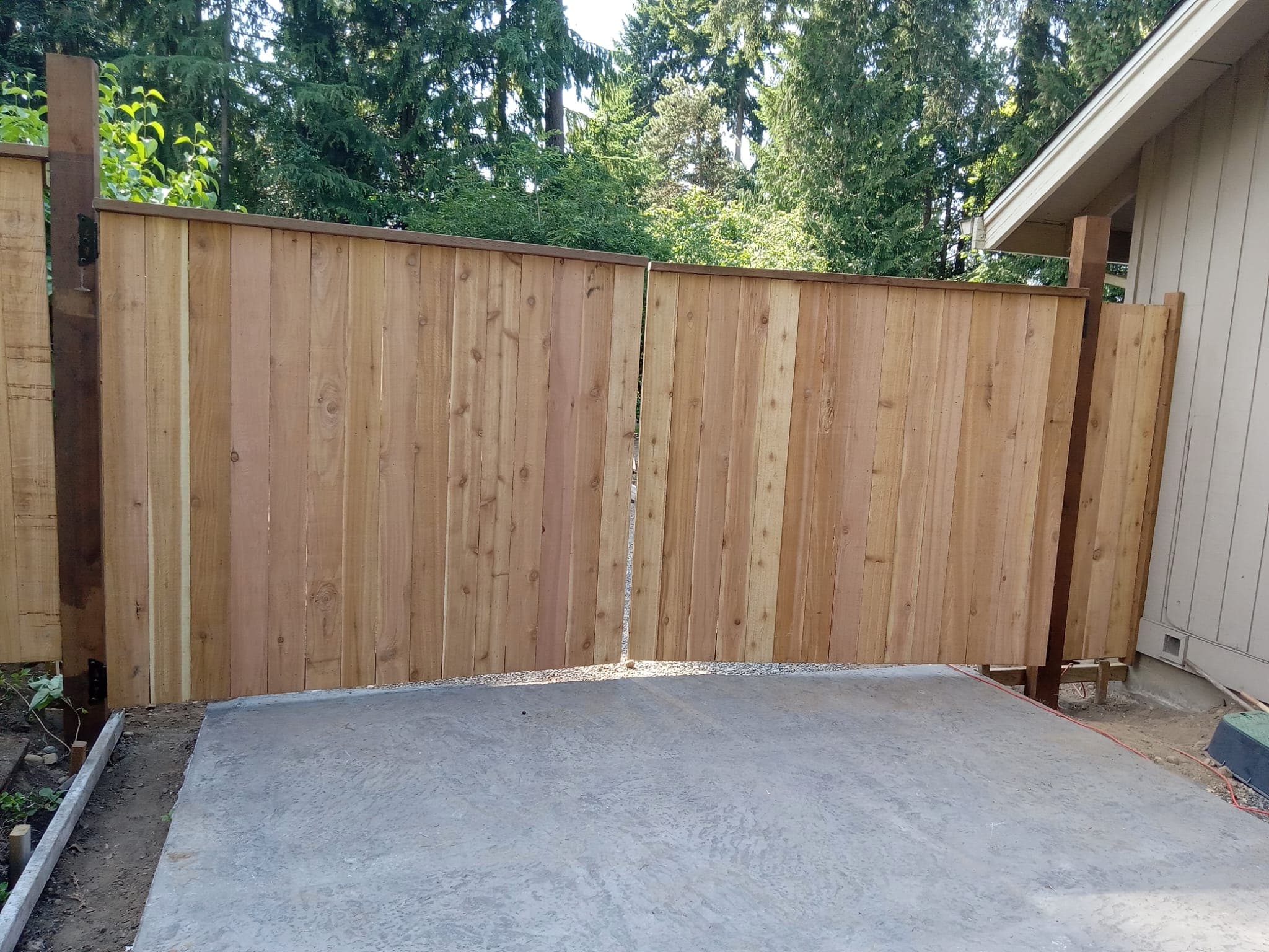 Custom cedar double gate closed with concrete pad in front