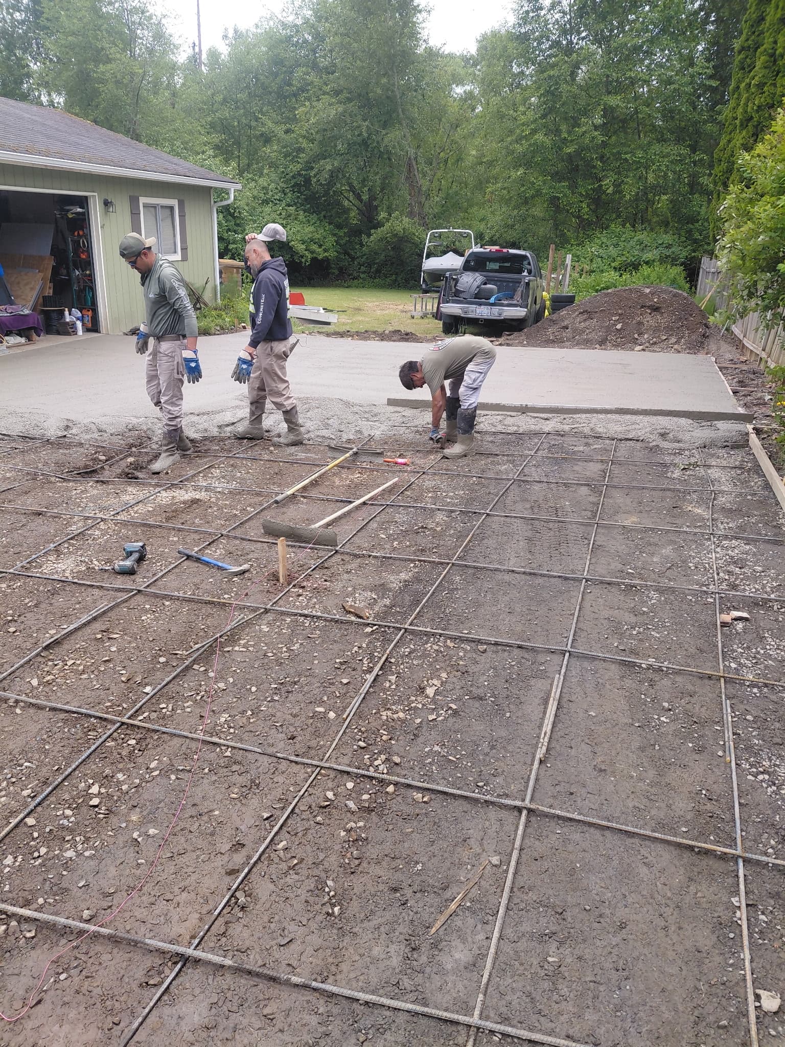 Three-person crew placing rebar and preparing for residential concrete pour