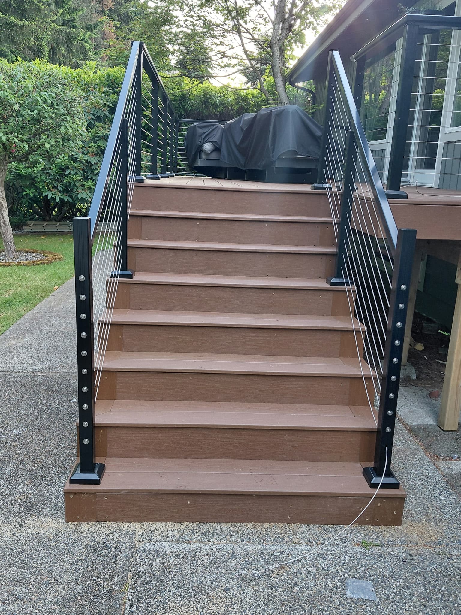 Straight-on view of finished composite deck stairs with dual cable railings