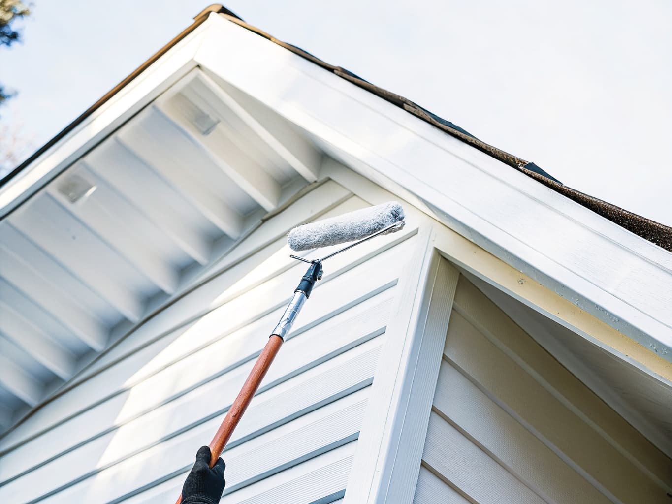 Exterior of a Pacific Northwest residential home being painted with a roller on extension pole