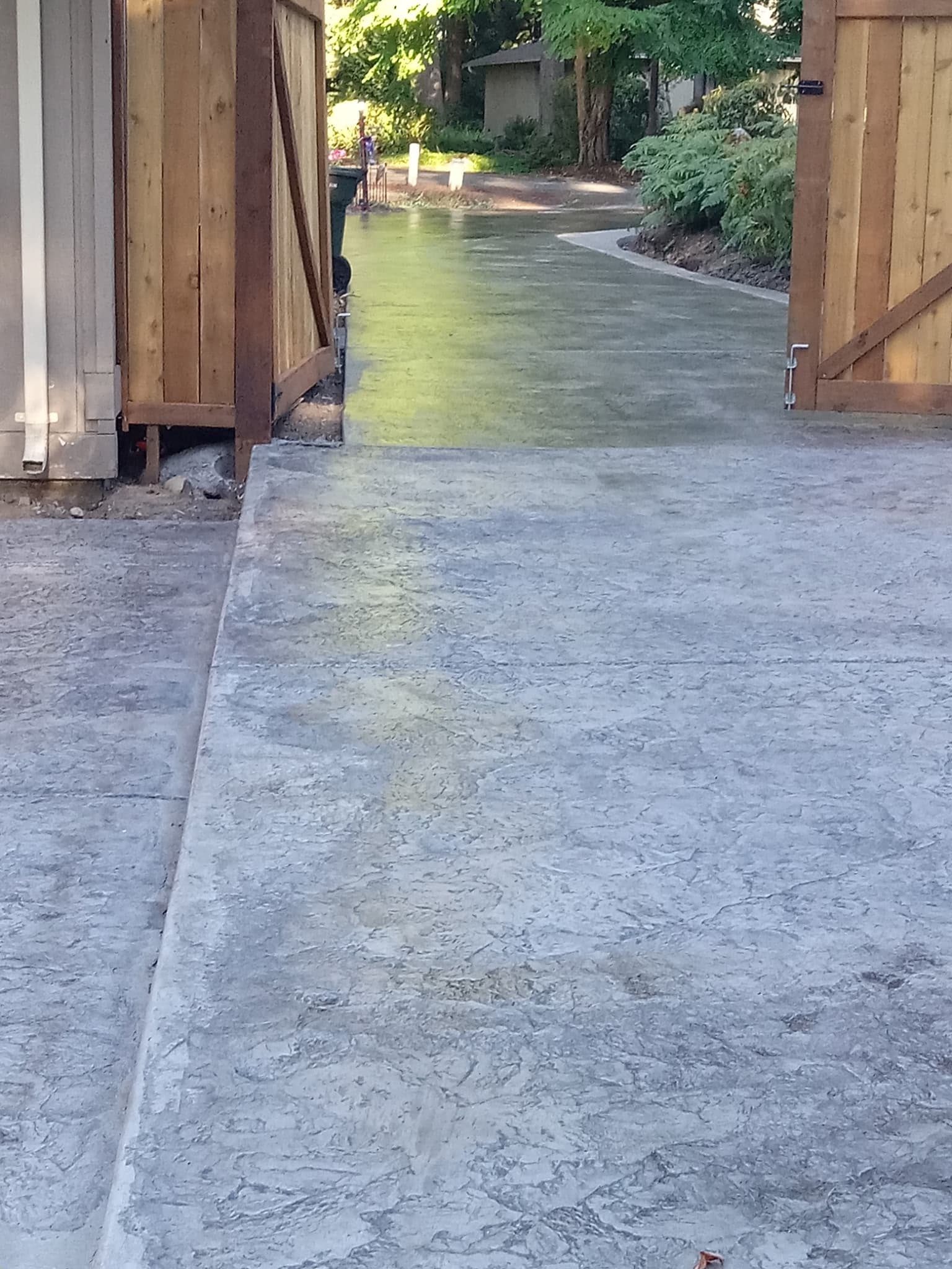 Stamped concrete driveway viewed through open cedar gate