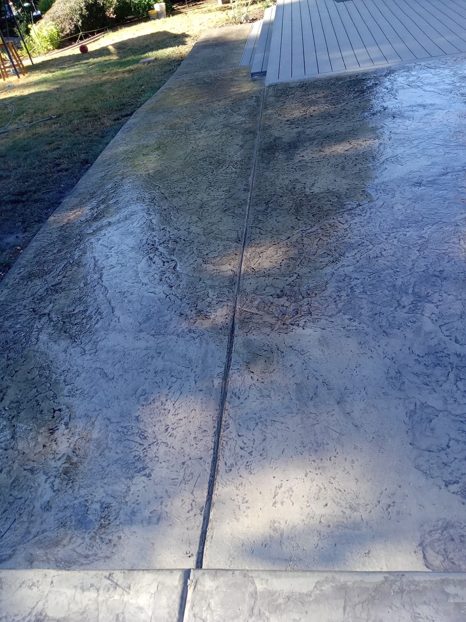 Stamped concrete patio surface adjacent to composite deck boards