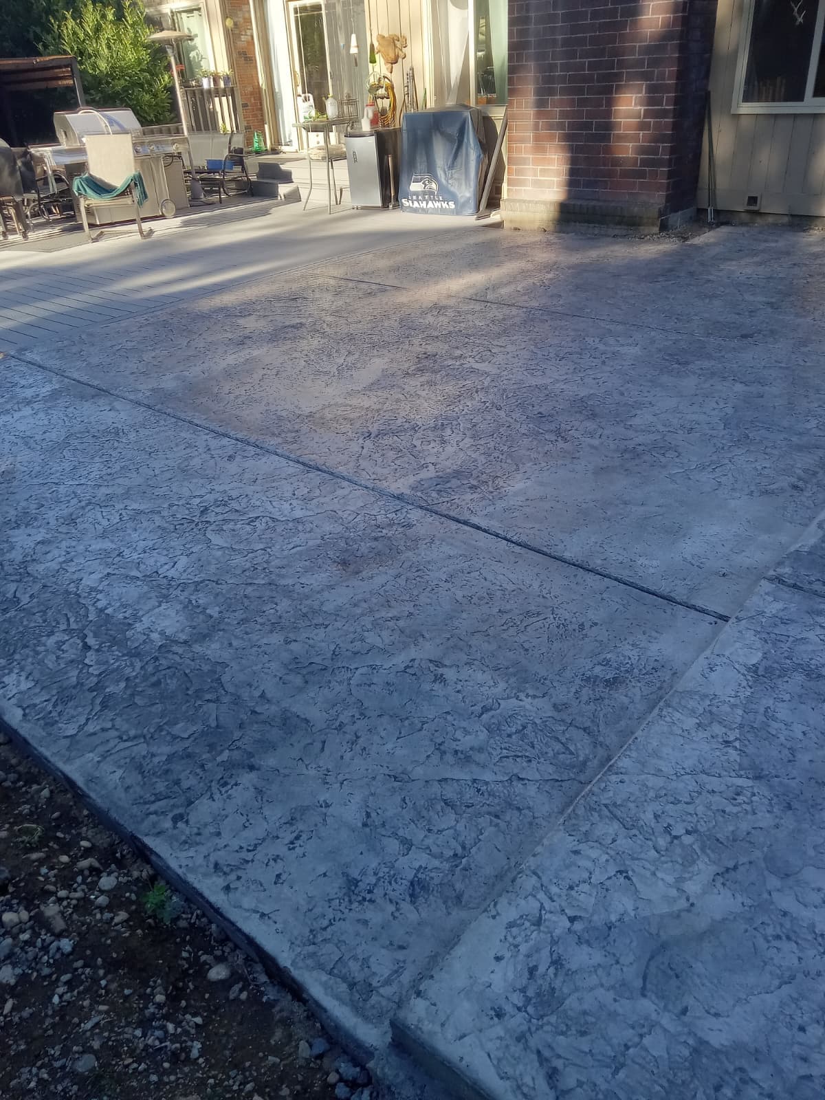 Finished stamped concrete patio with textured surface beside home