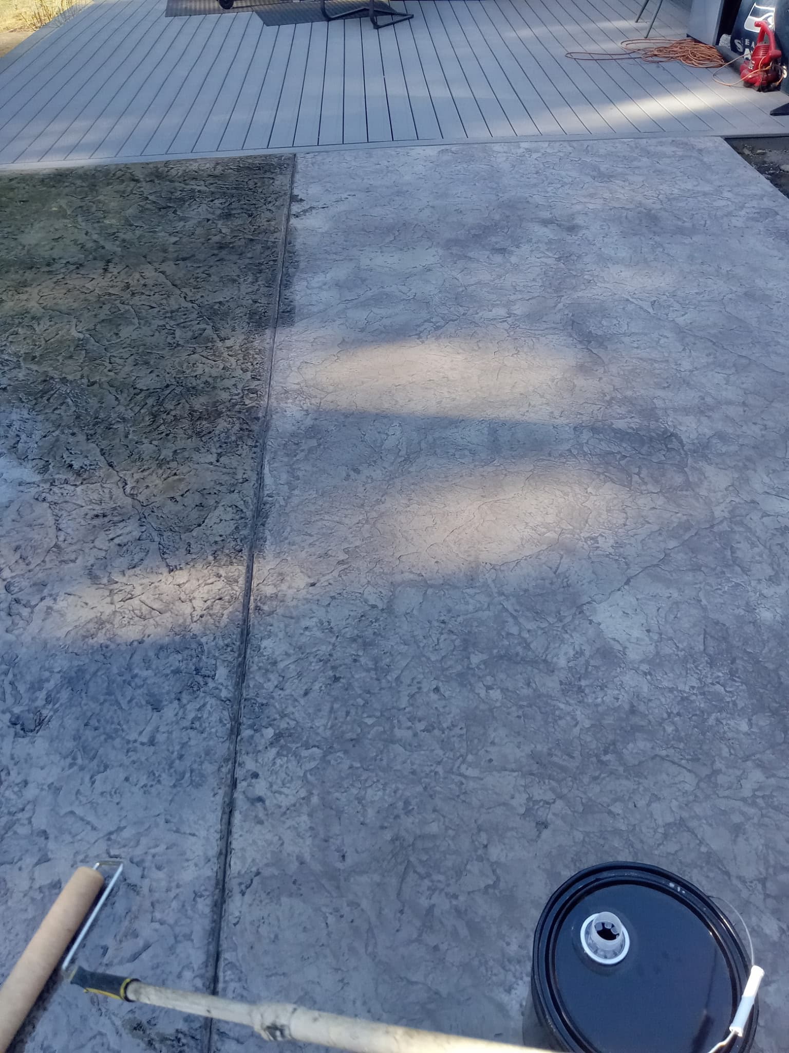 Stamped concrete being sealed next to composite deck